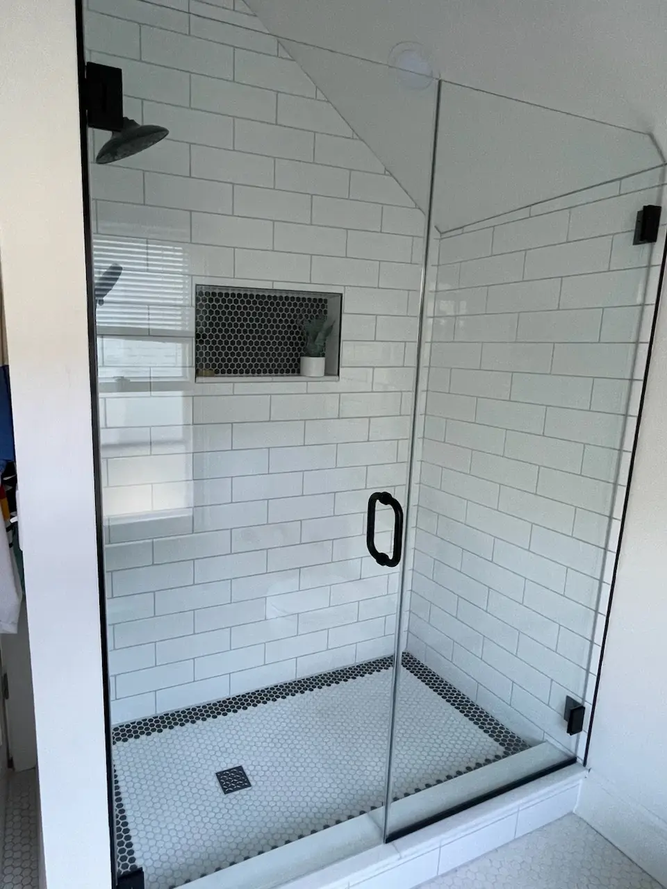 Glass-front shower under a sloped ceiling with black fixtures