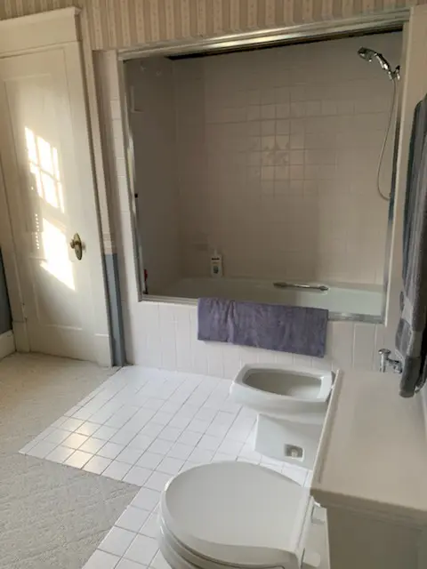 Before: tub with sliding glass doors and wallpaper
