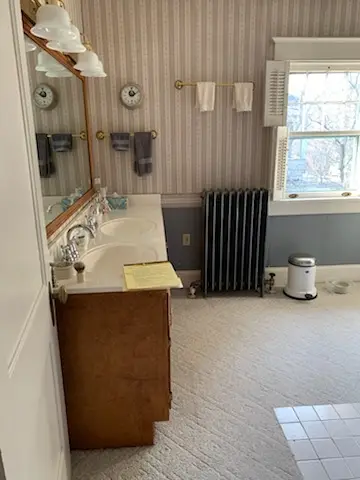 Before: carpeted bathroom with oak vanity and radiator