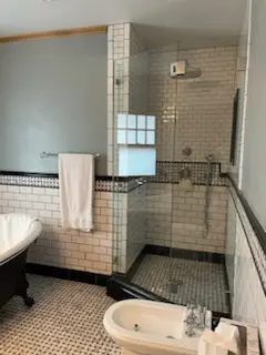 Glass shower with black trim tile and bidet