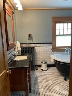 Dark wood vanity, painted radiator, and clawfoot tub