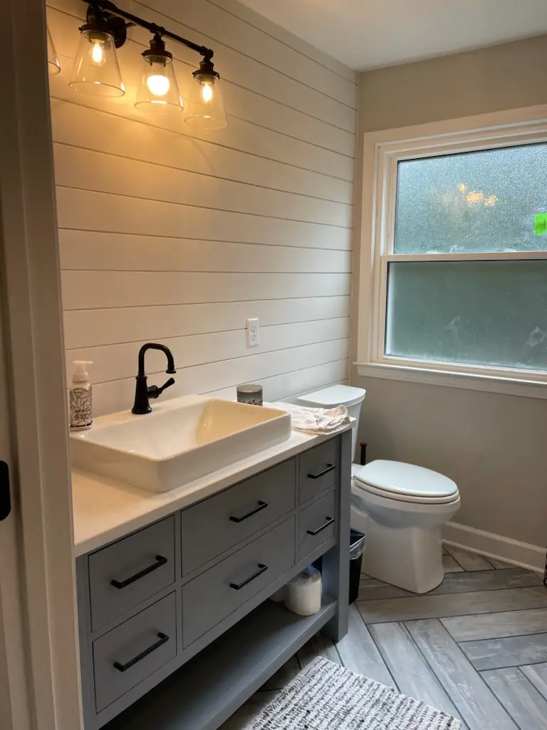 Gray vanity with vessel sink against a shiplap wall