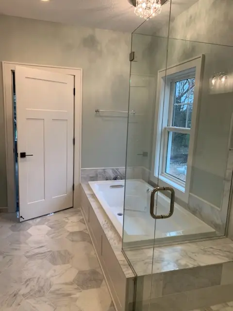 Finished master bath with soaking tub, glass shower, and chandelier