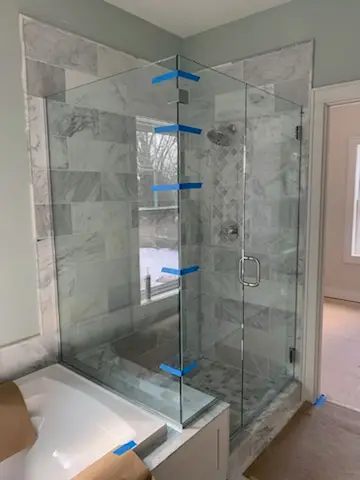 Frameless glass shower enclosure beside the tub deck