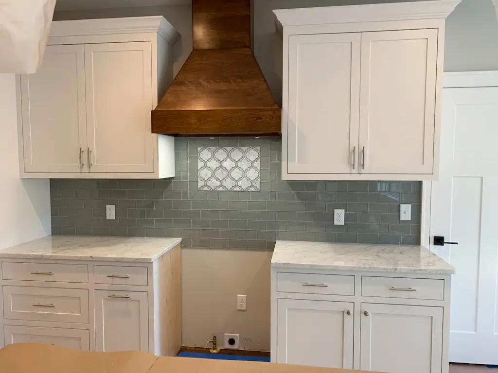 White inset cabinets, walnut hood, and arabesque tile inset during install