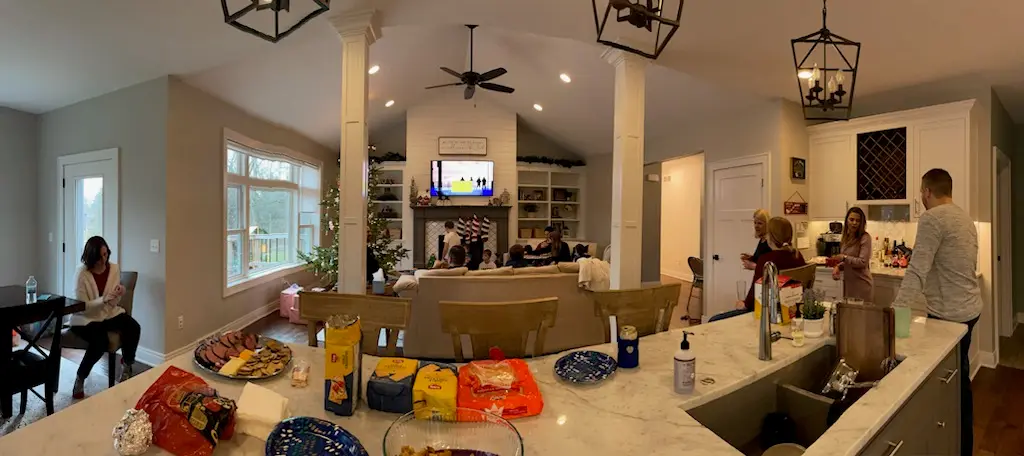 Panorama of the great room and kitchen during a holiday gathering