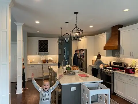 Range wall with wood hood and island under lantern pendants