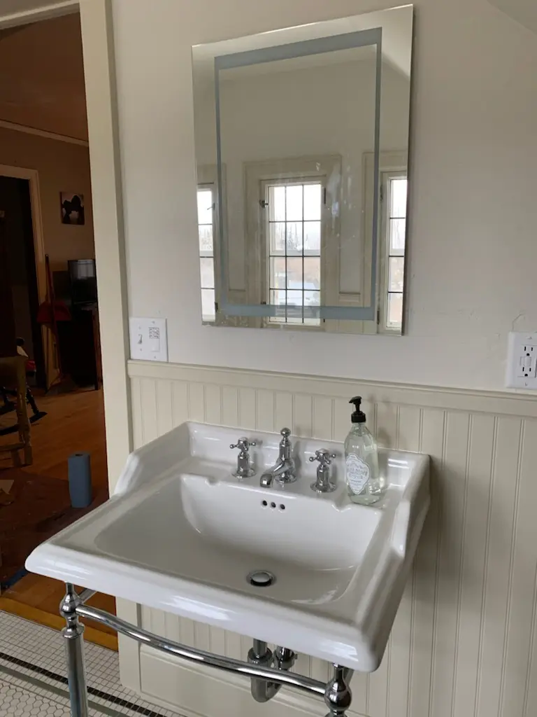 Console sink and beveled mirror against beadboard wainscot