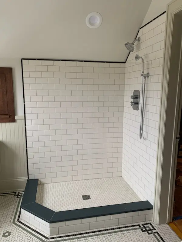Subway-tile walk-in shower with soapstone curb and hex floor
