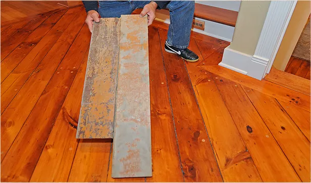 Salvaged boards being matched to a restored wide-plank pine floor during a period restoration