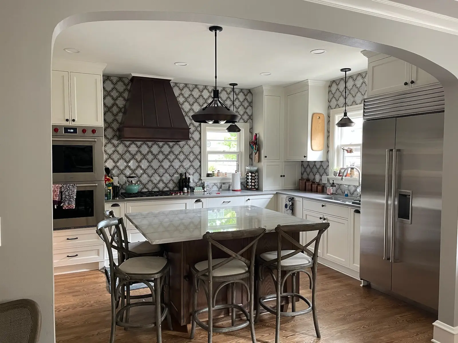 Wide view: steel hood, double ovens, and marble tile wall