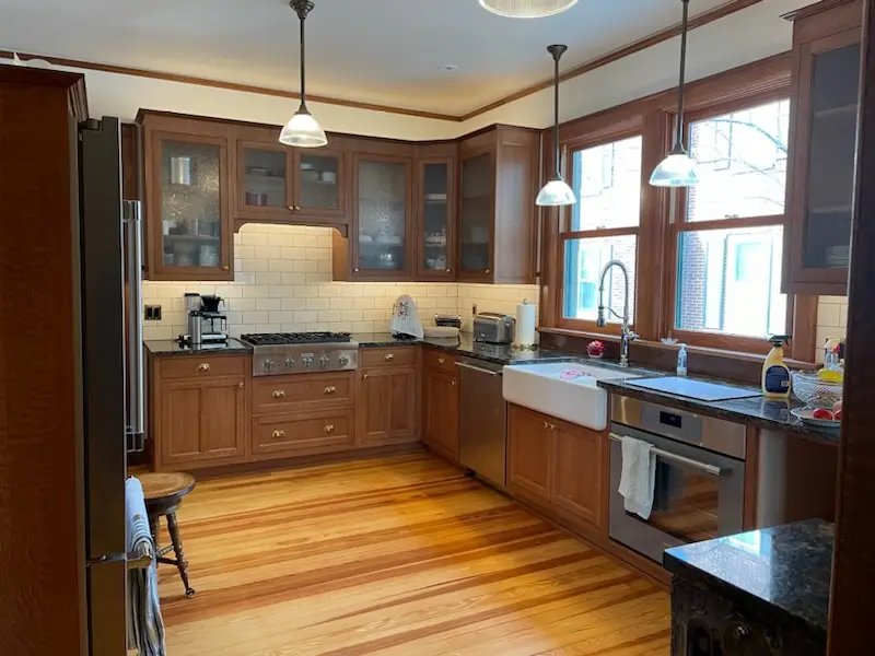 Period kitchen with glass-front cabinets, farmhouse sink, and heart-pine floor