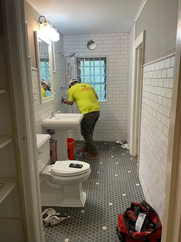 Plumber setting fixtures; pedestal sink and penny floor in place